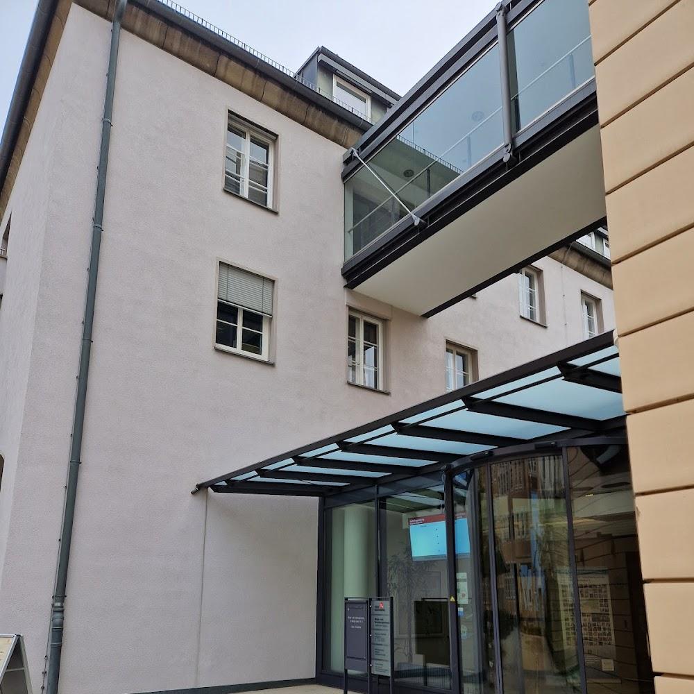 A white building with a glass walkway and an awning over a door.